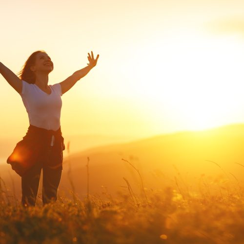 Happy woman   on the sunset in nature in summer with open hands